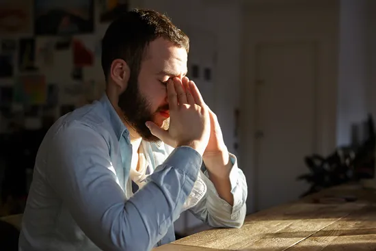 photo of anxious man sitting at kitchen table